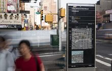 wayfinding totem in focus with people walking past blurred.