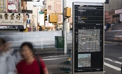 wayfinding totem in focus with people walking past blurred.