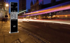 Elixir wayfinding totem at side of a road with light blurs of cars whizzing past.