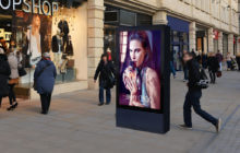 Double sided 75" Digital 6 sheet outdoor display on a side walk next to a retail shop.